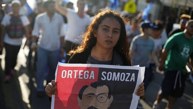 A demonstrator holds a sign showing Nicaraguan President Daniel Ortega and former President Anastasio Somoza during a protest against police violence and the government of President Ortega in Managua