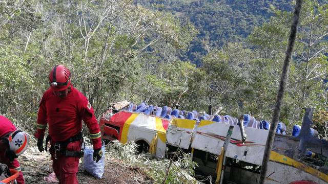 Members of a rescue team are seen next to a crashed bus where dozens of people died and others were injured, in the route La Paz-Yungas north of La Paz