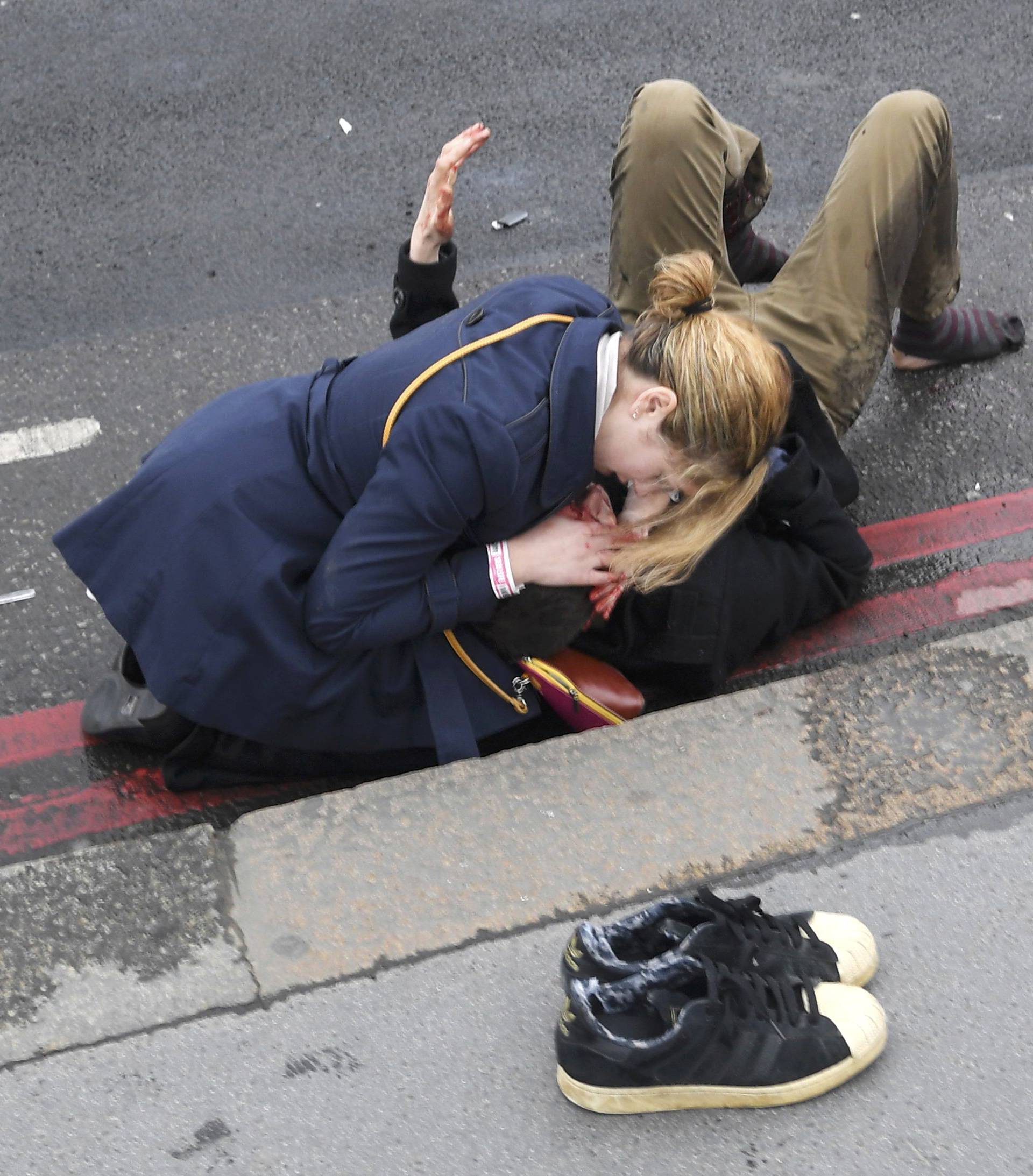 A woman assist an injured person after an incident on Westminster Bridge in London