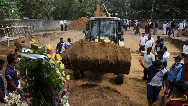 Men coordinate a mass burial of victims at a cemetery near St. Sebastian Church in Negombo