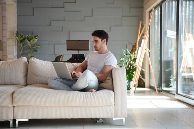 Young man using laptop while sitting in living room