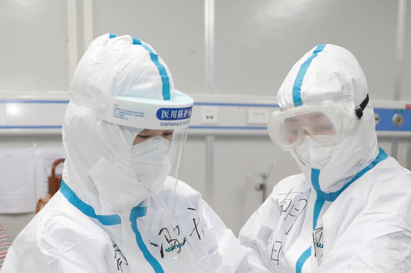 Medical worker writes down a patient's dietary information on a colleague's protective suit inside Leishenshan hospital in Wuhan