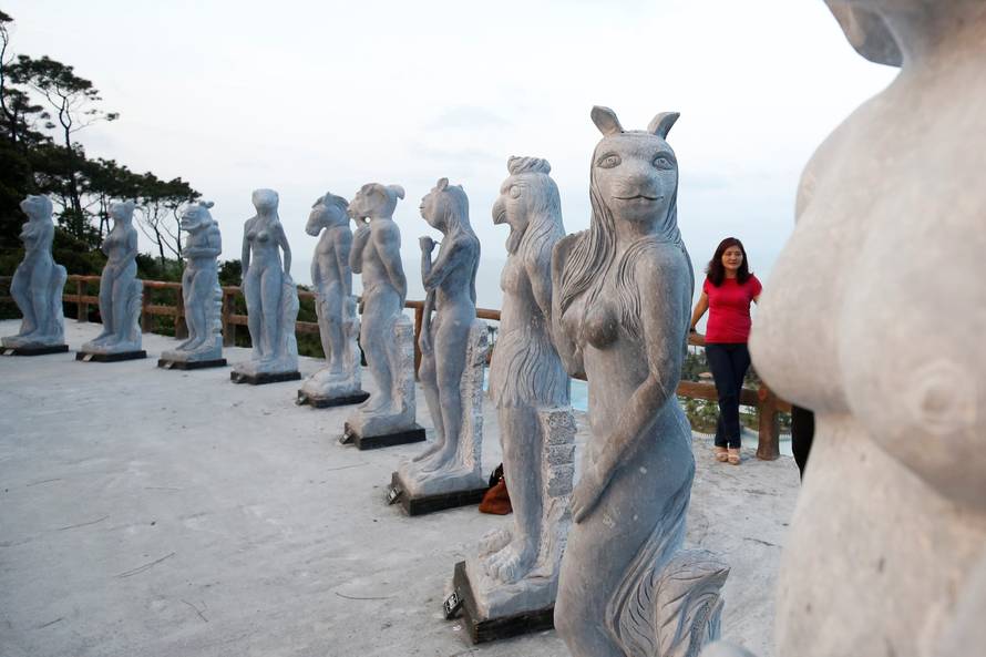 A woman stands near godlike sculptures with animal heads and human genitalia at Hon Dau resort in Hai Phong city, east of Hanoi