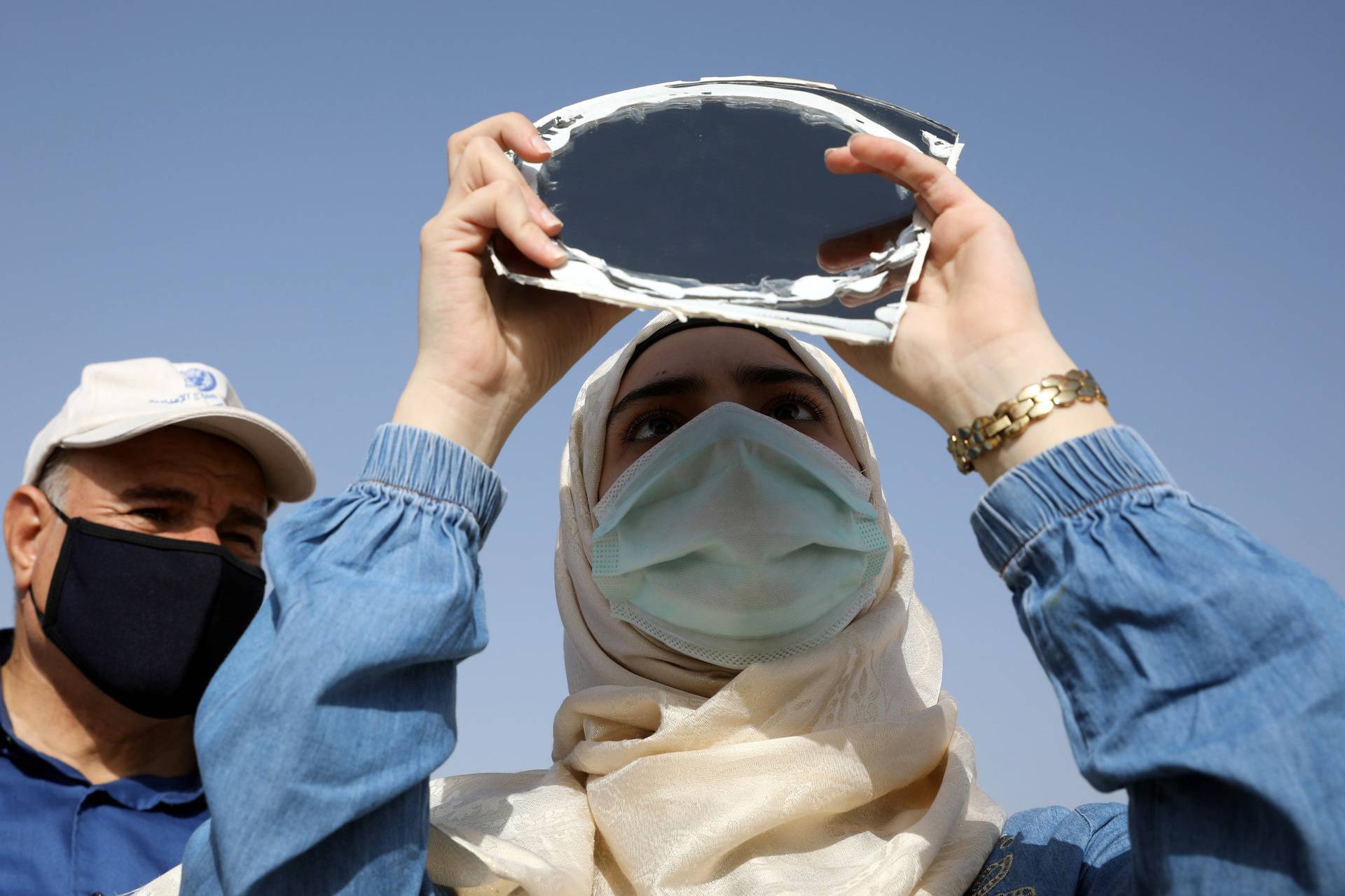 People observe a partial solar eclipse at the Amman Citadel, an ancient Roman landmark, in Amman