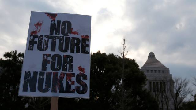 Anti-nuclear protesters raise a placard during a rally in front of the parliament building in Tokyo, Japan