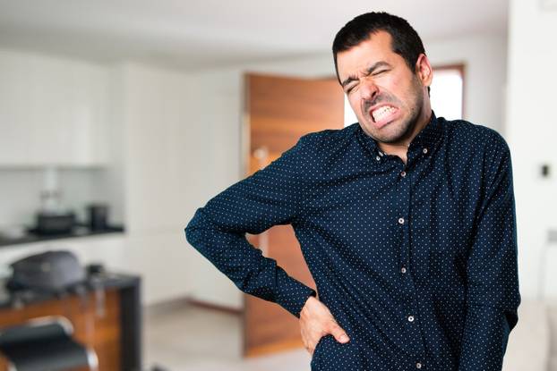 Handsome man with back pain inside house