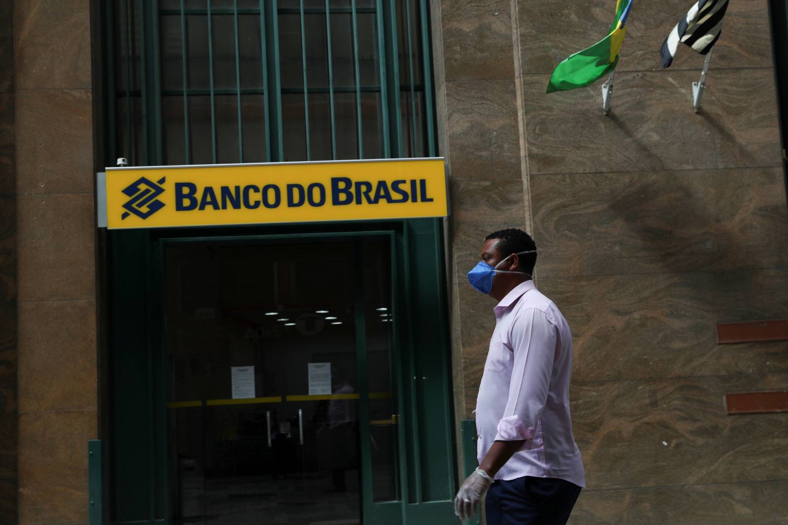 A man wearing a protective face mask and gloves walks in front of Banco do Brasil (Bank of Brazil) during the coronavirus disease (COVID-19) outbreak in Sao Paulo