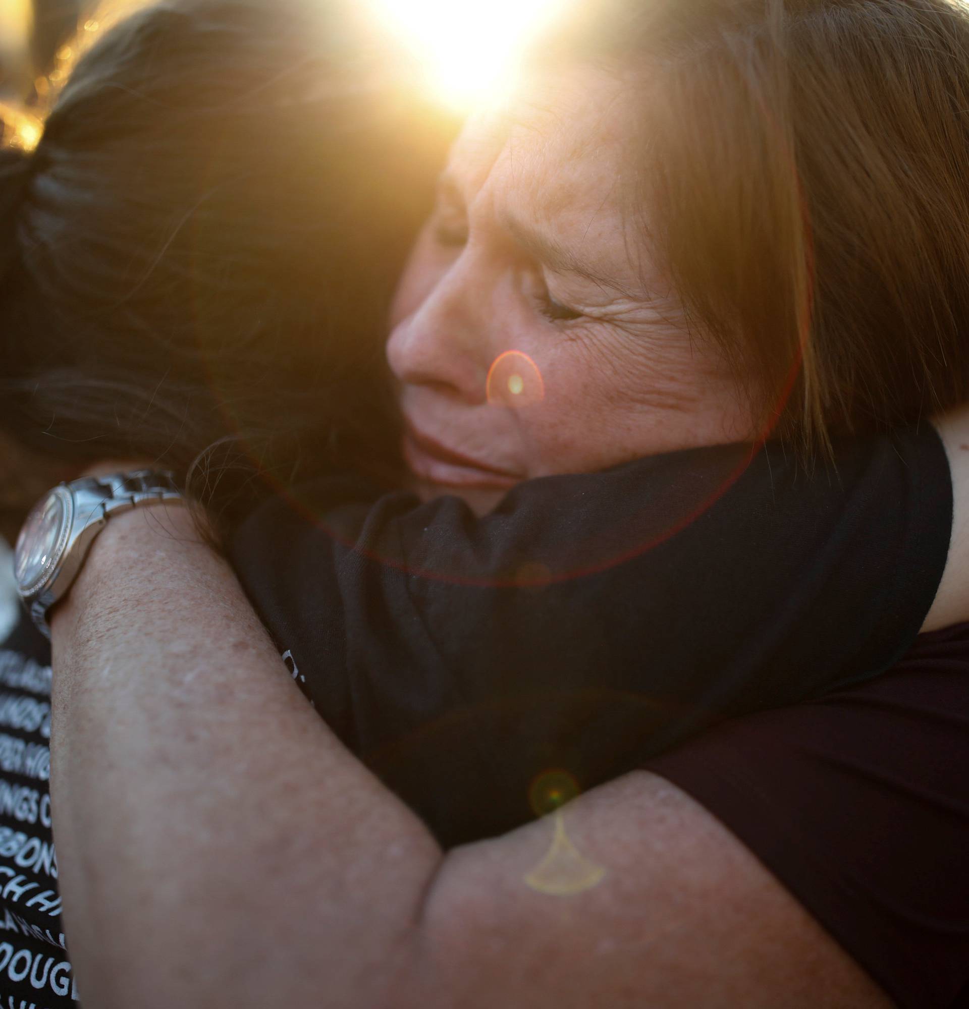 Women react during a candlelight vigil for victims of yesterday's shooting at nearby Marjory Stoneman Douglas High School, in Parkland