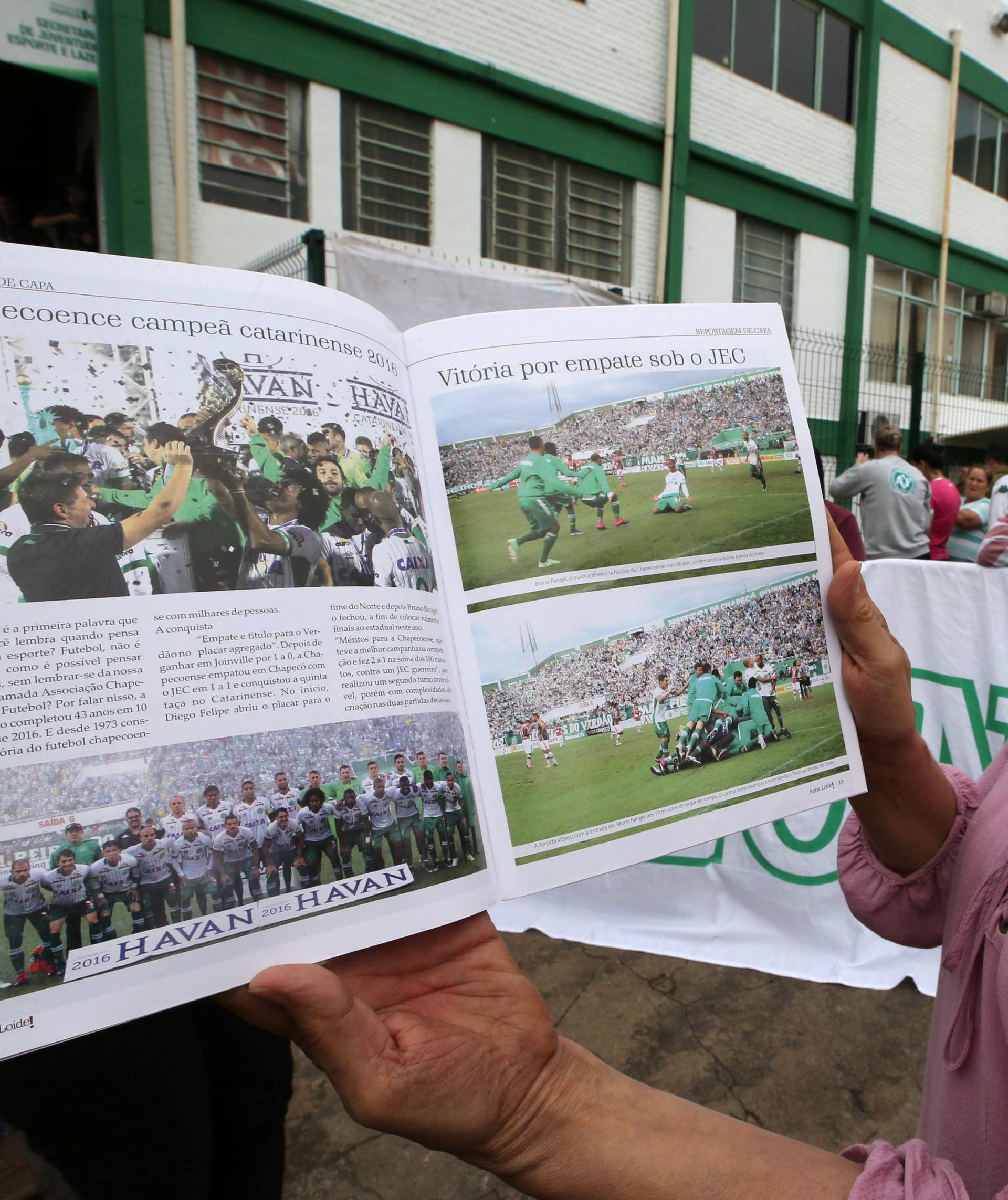 A fan of Chapecoense soccer team shows a magazine of the team in front of the Arena Conda stadium in Chapeco