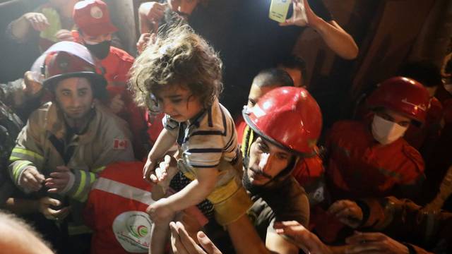 Rescuers carry a child that was evacuated from a building after a fuel tank exploded in the al-Tariq al-Jadida neighborhood of Beirut