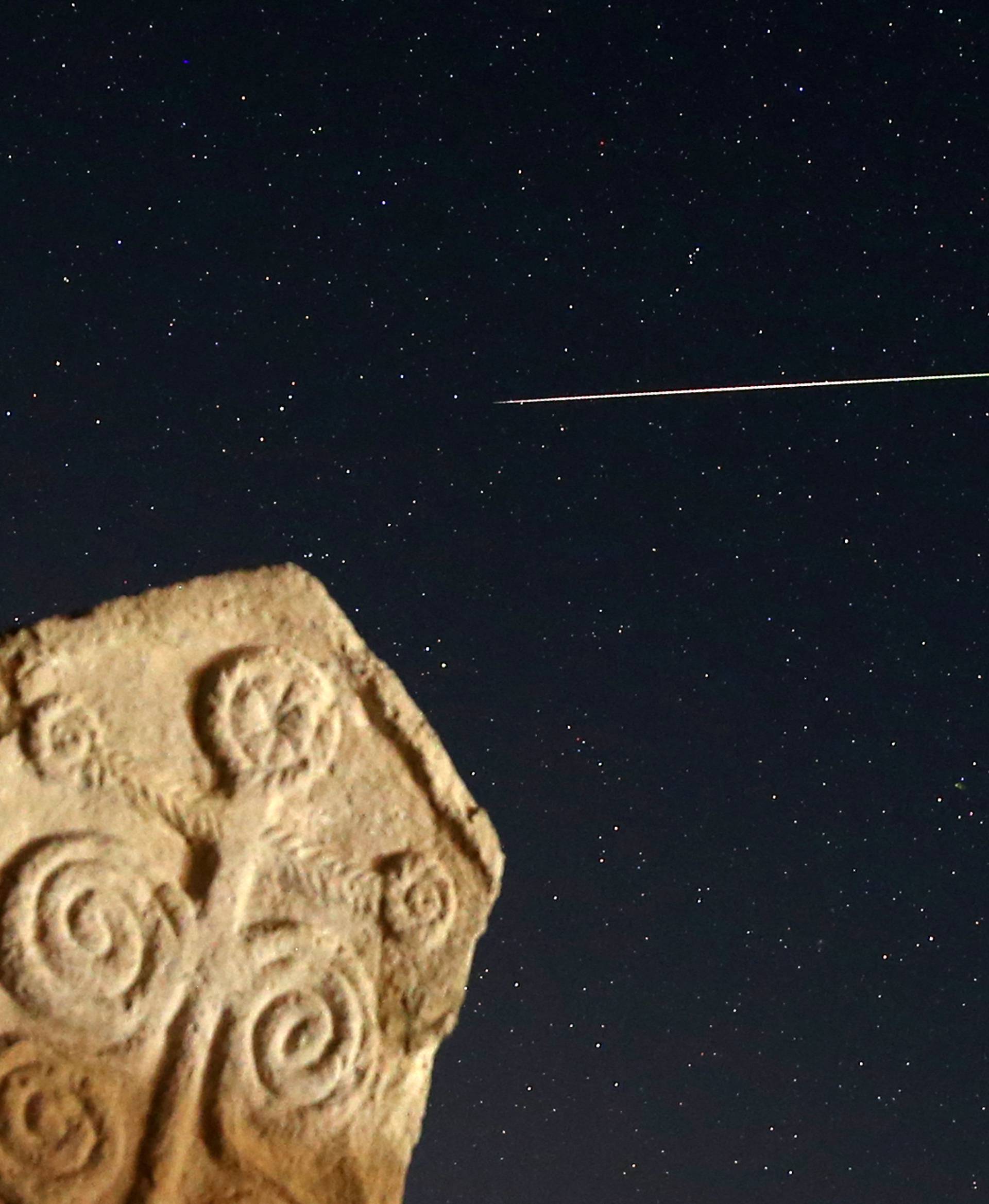 A meteor streaks past stars in the night sky above medieval tombstones in Radmilje near Stolac, south of Sarajevo