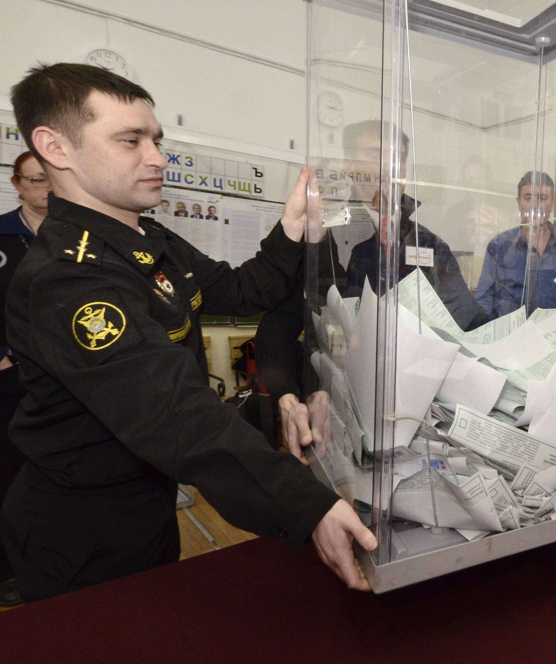 Members of a local election commission empty a ballot box before starting to count votes during the presidential election in Vladivostok