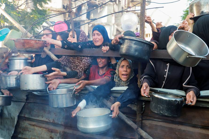 Palestinians gather to receive food from a charity kitchen amid hunger crisis, in Gaza City