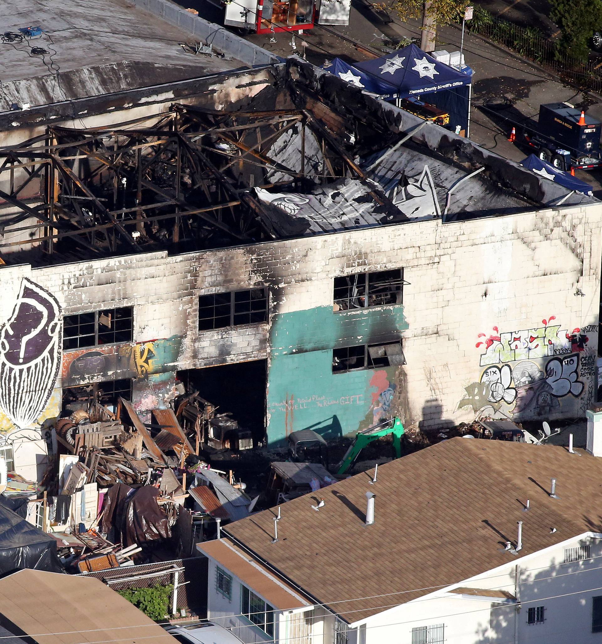 FILE PHOTO:    Recovery teams examine the remains of the warehouse that caught fire in Oakland