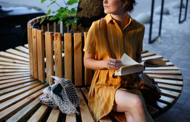 girl sits on a bench and reads a book 