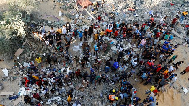 Palestinians search for casualties under the rubble of a house destroyed in Israeli strikes in Khan Younis