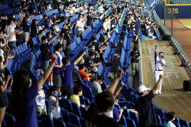 Baseball fans dance to support their team while wearing face masks during the first professional league game with audience, since the outbreak of the coronavirus disease (COVID-19), in Taipei