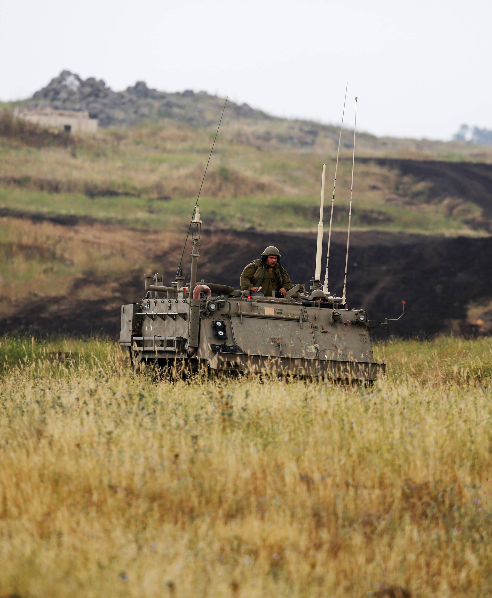 An Israeli soldier sits on an APC as it drives near the Israeli side of the border with Syria in the Israeli-occupied Golan Heights