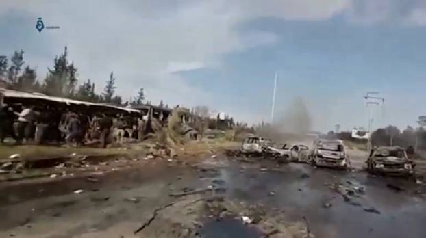 A still image taken from a video uploaded on social media on April 15, 2017, shows burnt out buses on road, scattered debris lying nearby and injured people being tended to away from buses said to be in Aleppo