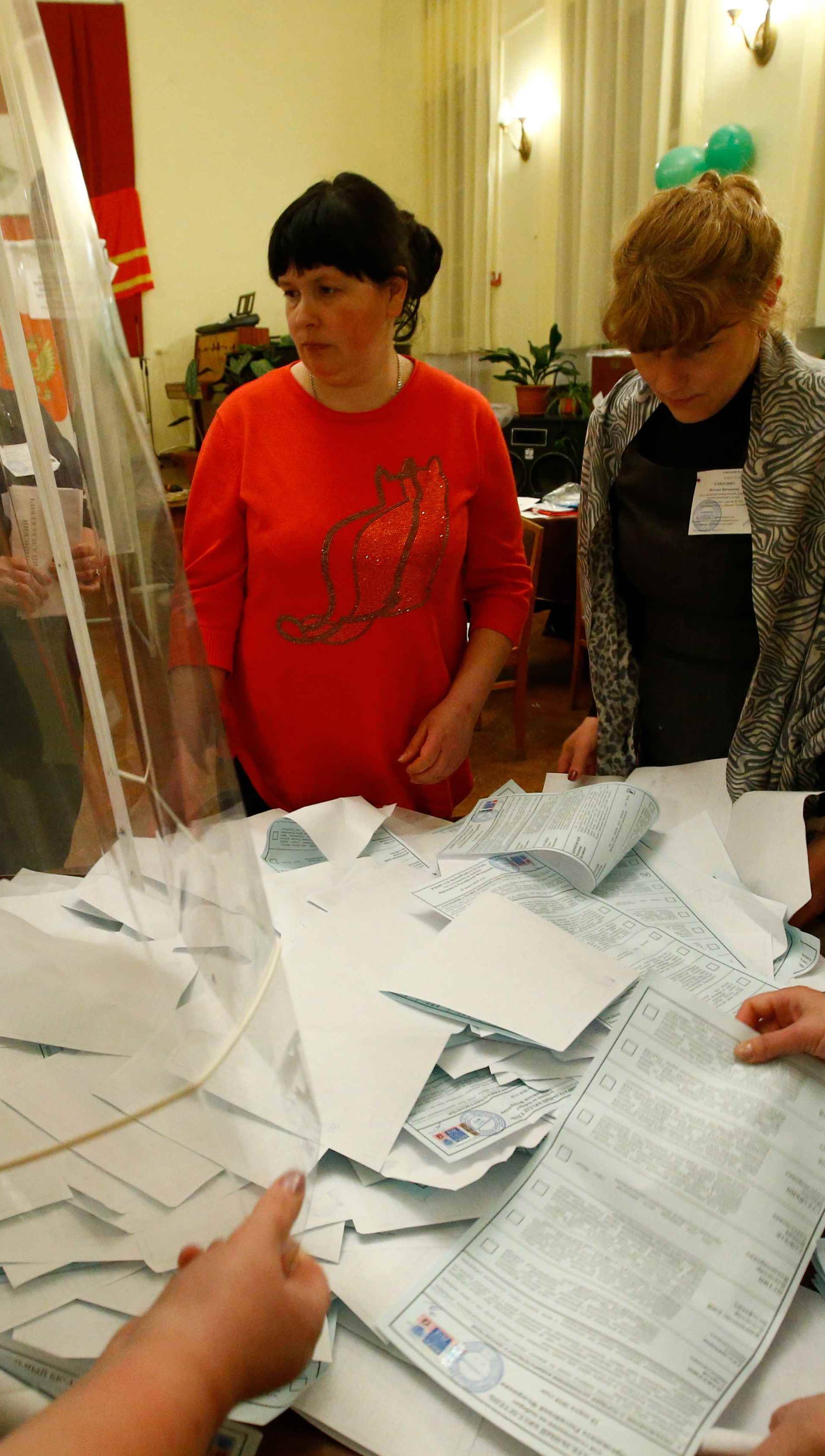 Members of a local election commission empty a ballot box before starting to count votes during the presidential election at a polling station in a settlement in Smolensk Region