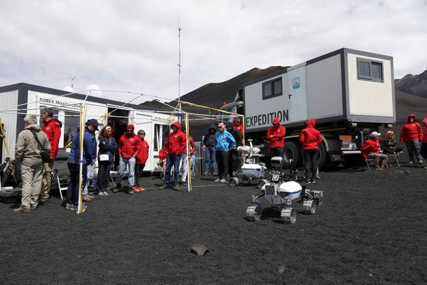 Scientists from German Aerospace Center stand in front of a robot on the Mount Etna