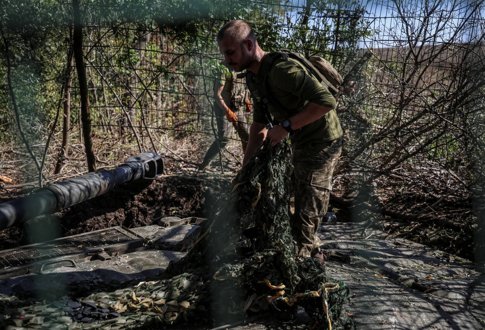 Ukrainian servicemen camouflage a self propelled howitzer after firing towards Russian troops in Donetsk region