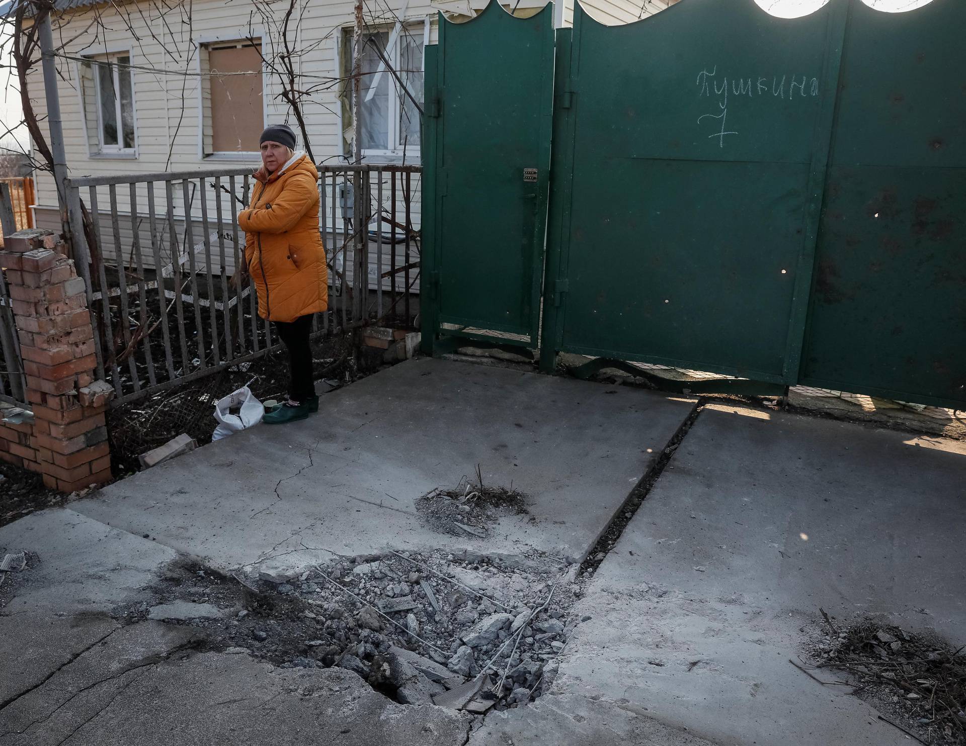 Local resident stands near her home as shell craters are seen after yesterday's shelling near the front line near the city of Novoluhanske