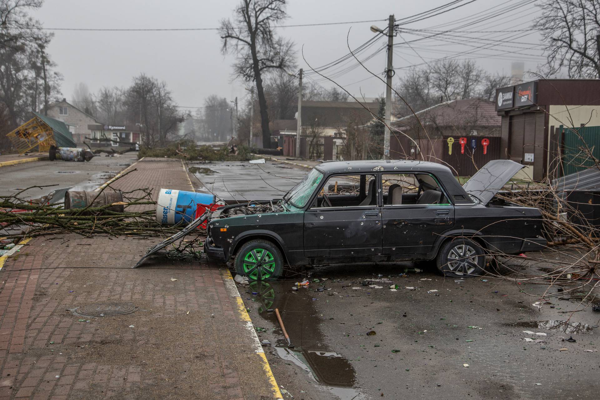 A car with bullet holes is seen on an empty street in the town of Bucha