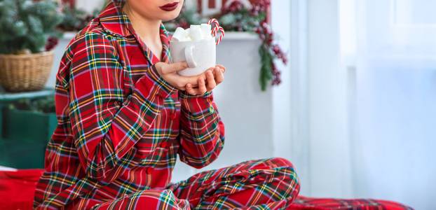 Christmas morning, girl in pajamas with a cup of hot cocoa with marshmallows. Selective focus.