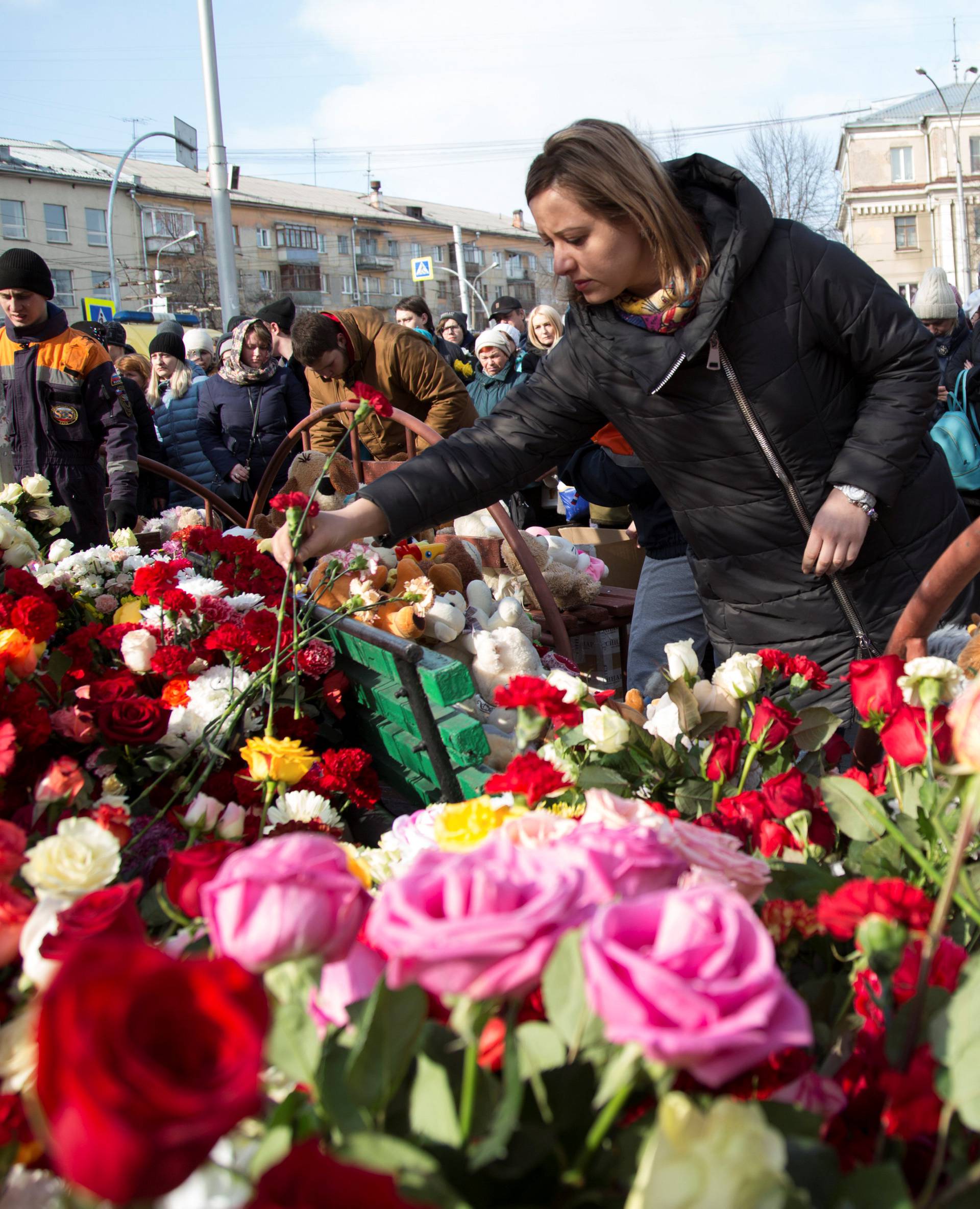 People place flowers at a makeshift memorial for the victims of a shopping mall fire in Kemerovo