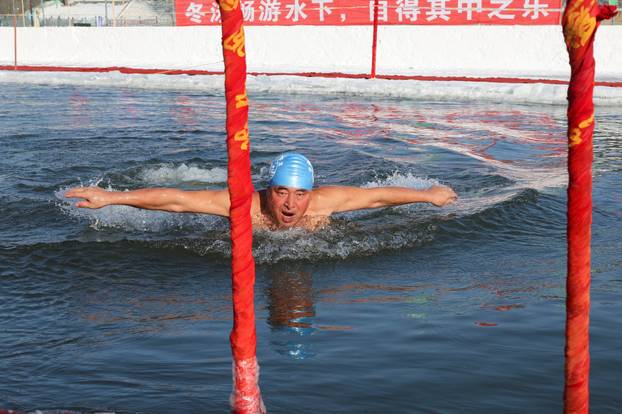 Locals participate in winter swimming events during the annual ice and snow sculpture festival, in Harbin