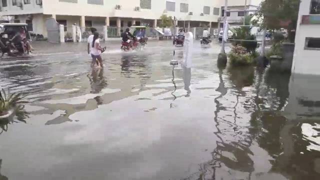 Pedestrians and vehicles move along a flooded street after a tropical depression descended upon Daet, Camarines Norte