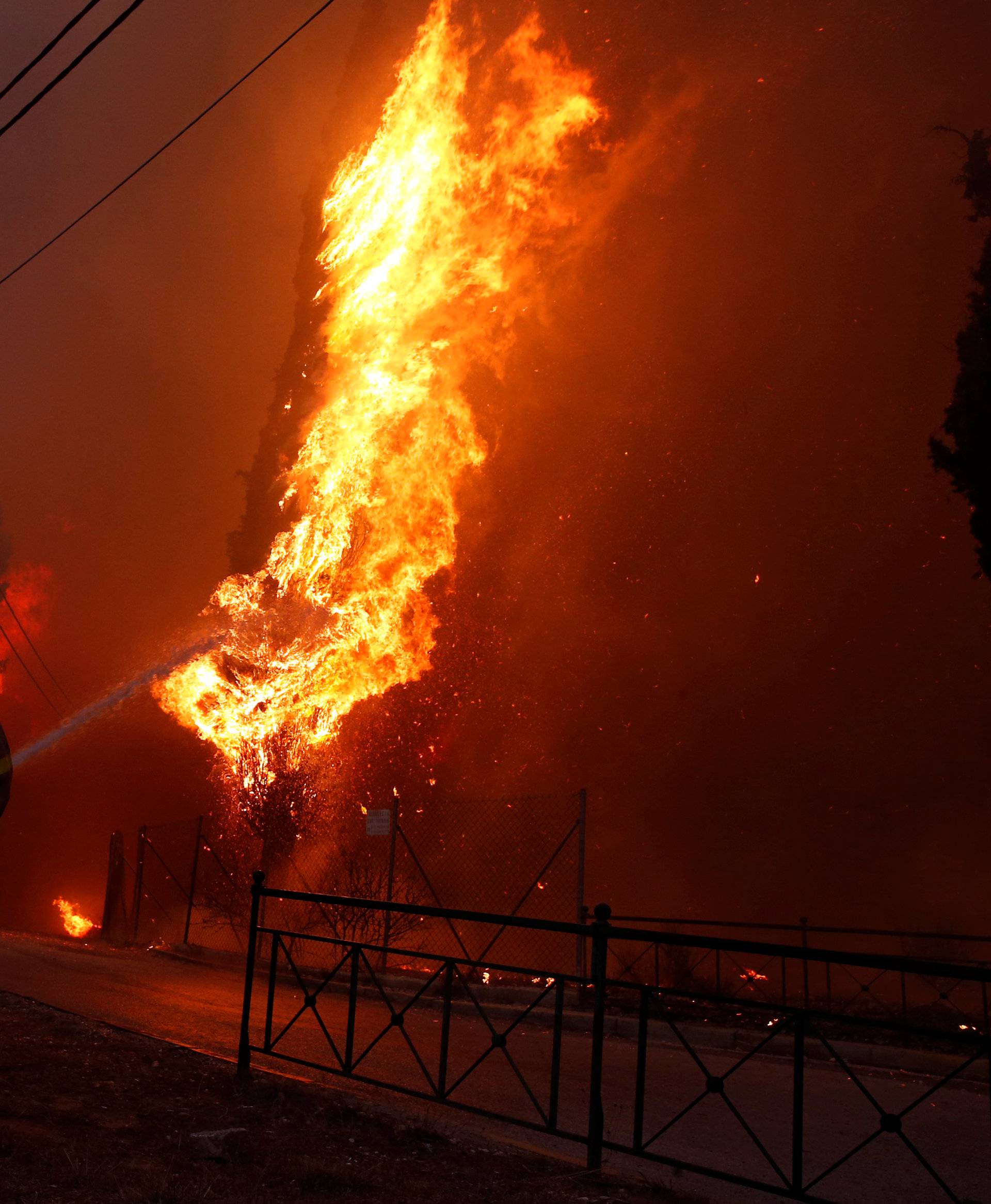 A firefighter tries to extinguish a wildfire burning in the town of Rafina, near Athens