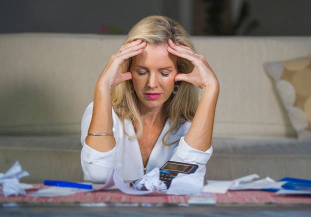 worried and desperate blond woman calculating domestic money exp