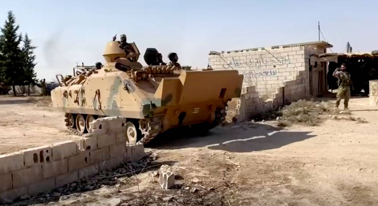 A Syrian rebel tank carrying soldiers leaves their base near Tal Abyad