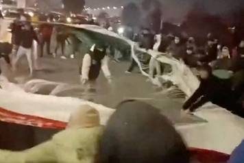 People tear down an Iranian flag after it was taken down in Mashhad, Razavi Khorasan Province