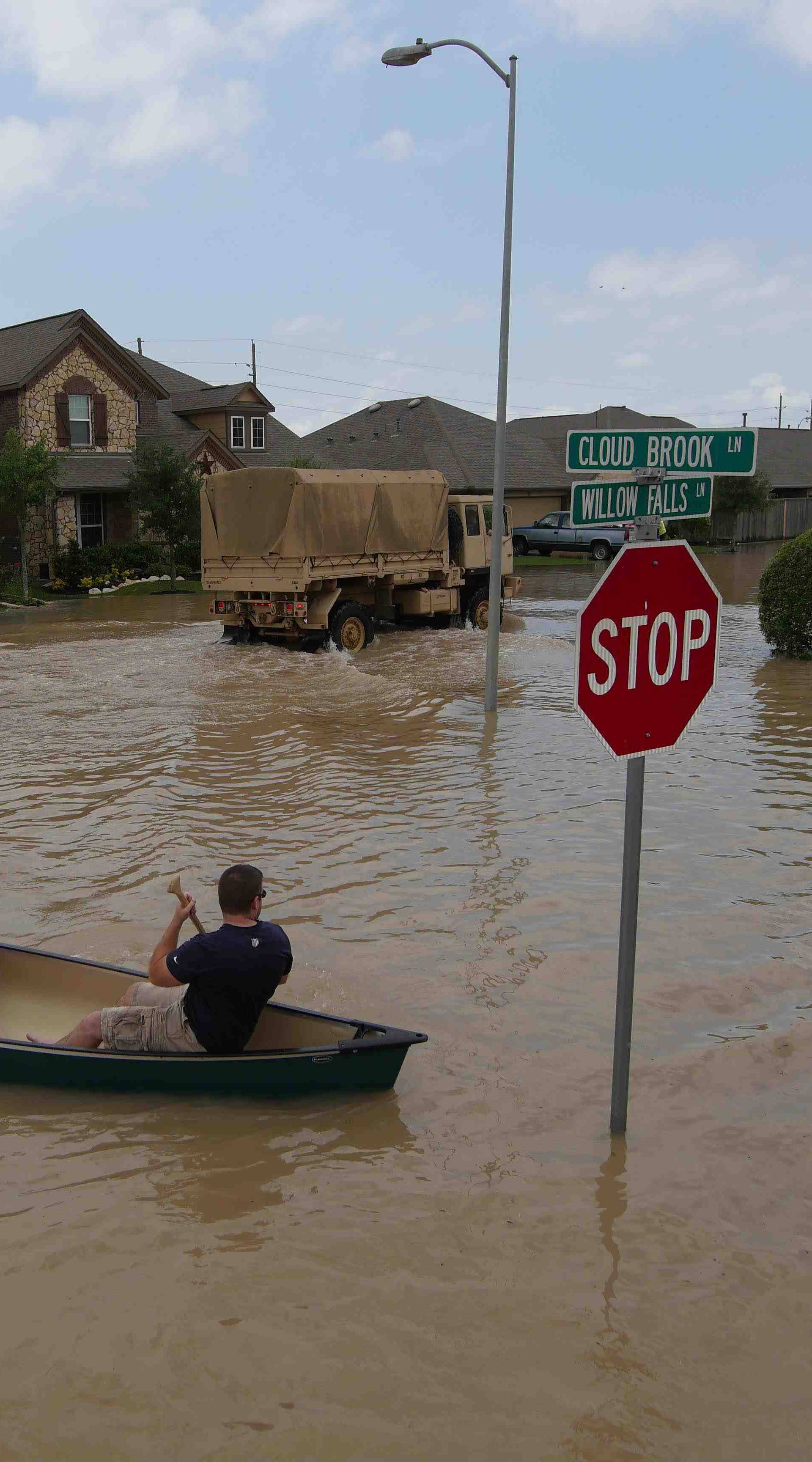 A woman holds a baby in a canoe as Texas Guardsmen arrive to assist after flooding in Brookshire