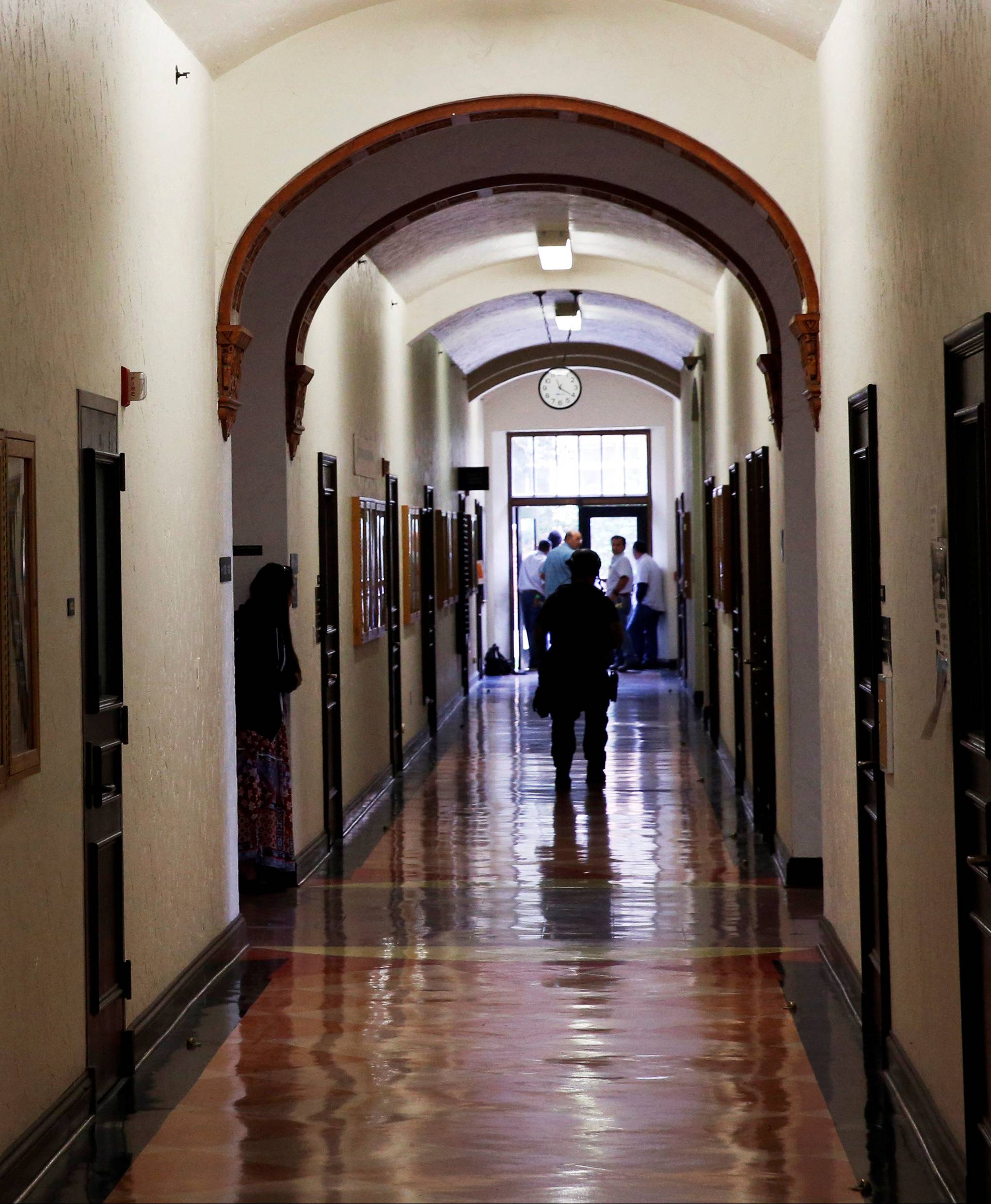 A student at the University of California, Los Angeles (UCLA) peers around the corner of a hallway in the School of Education building after the campus was placed on lockdown following reports of a shooter in Los Angeles