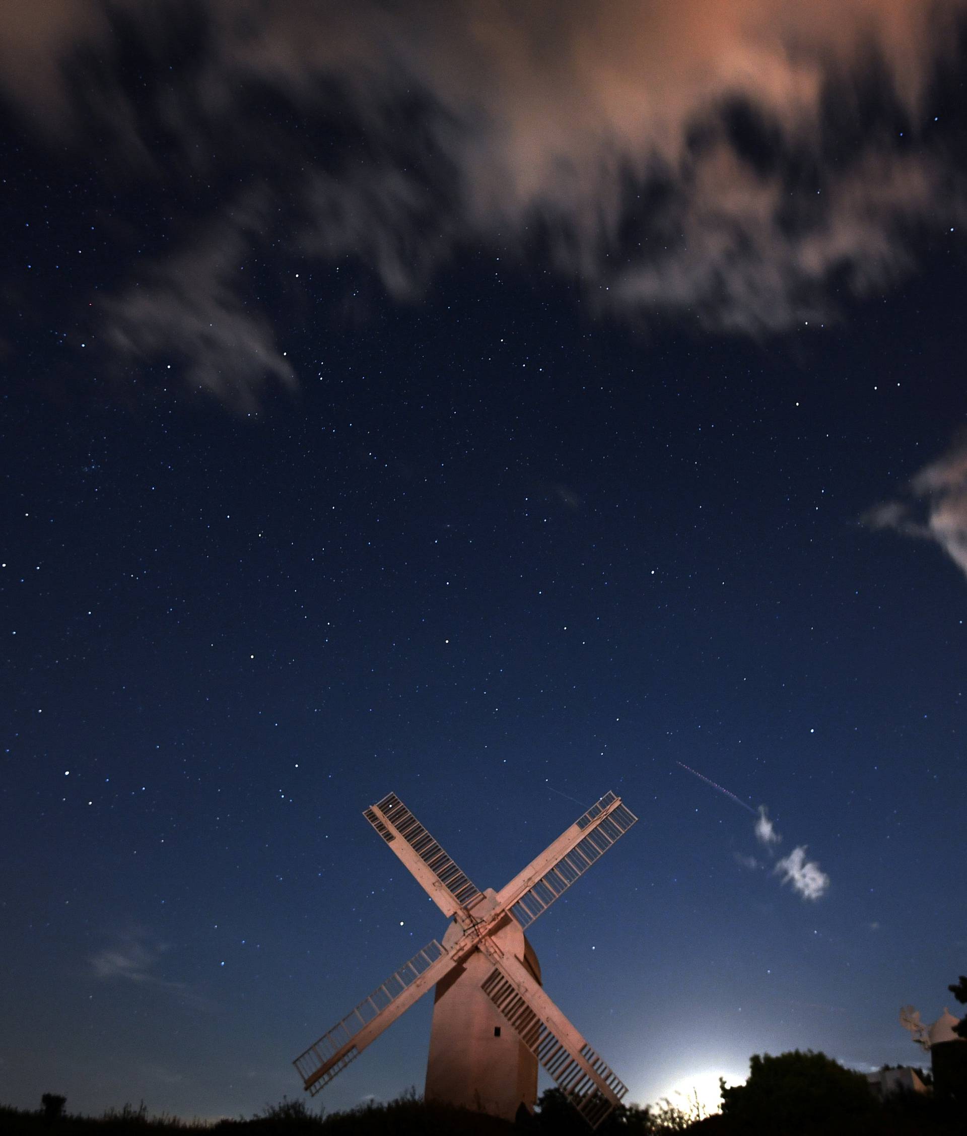 A meteor streaks past stars in the night sky above the Jill Windmill, during the Perseid meteor shower in Brighton