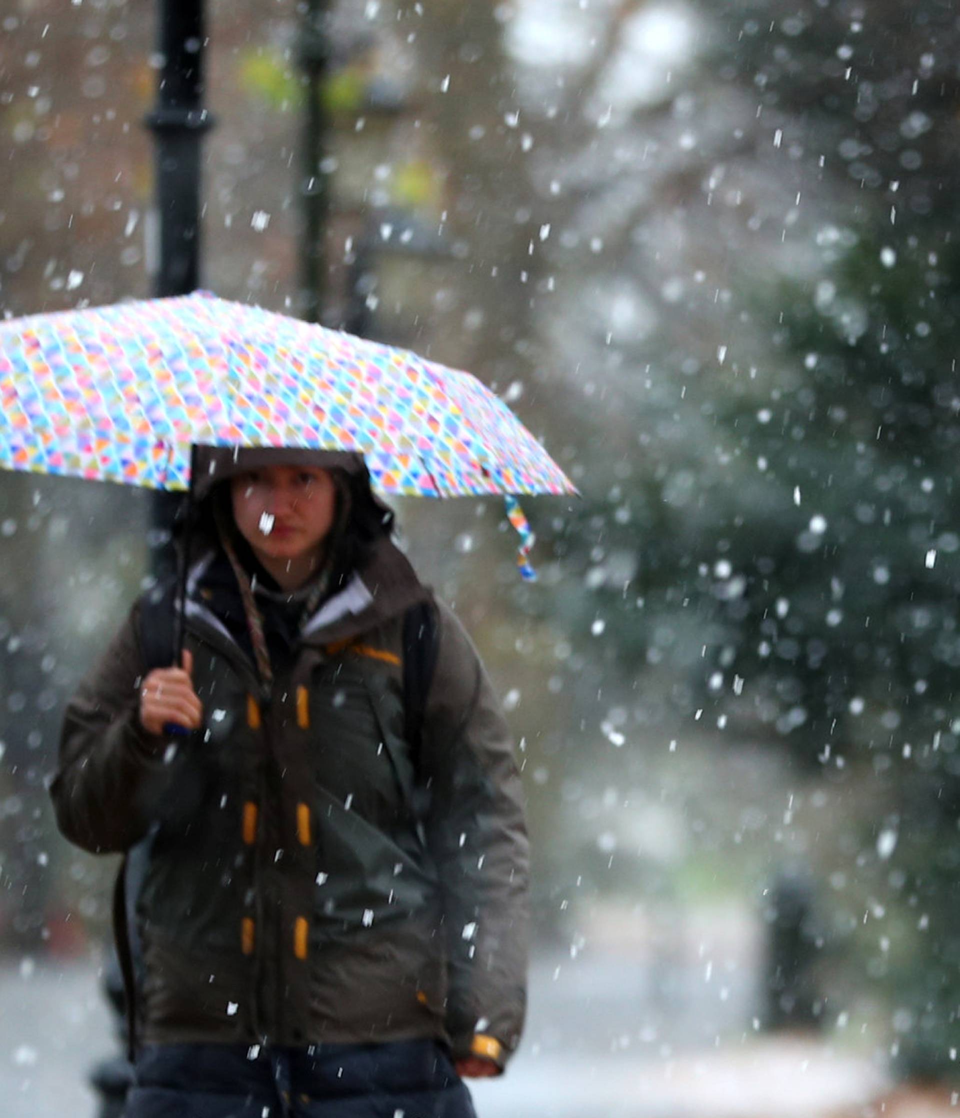 A woman walks through the snow in Battersea Park, London