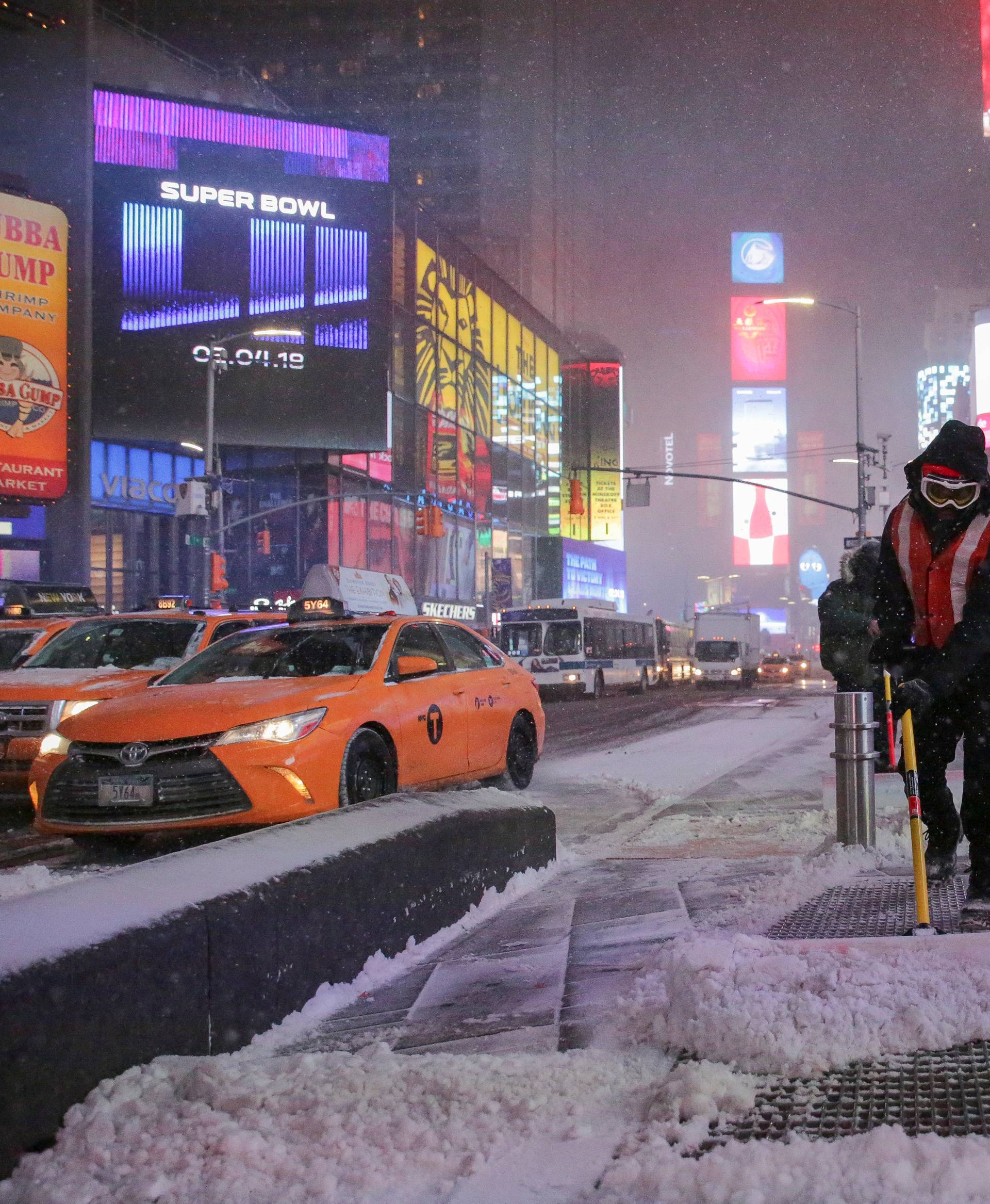 Workers remove snow during a snowstorm in Times Square in Manhattan
