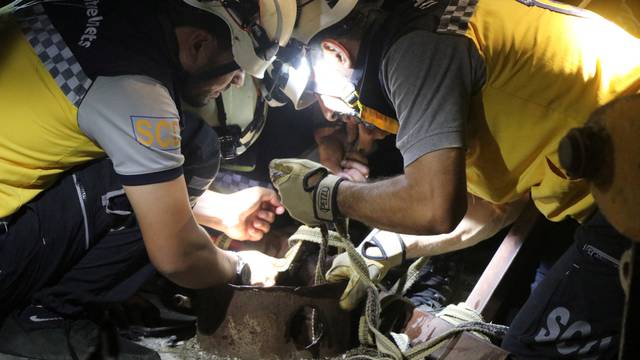 Members of Syria Civil Defence (White Helmets) try to rescue a child who fell inside a well in Tell Awar