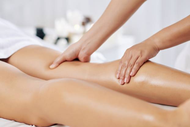 Hands,Of,Massage,Therapist,Massaging,Legs,Of,Young,Woman,In