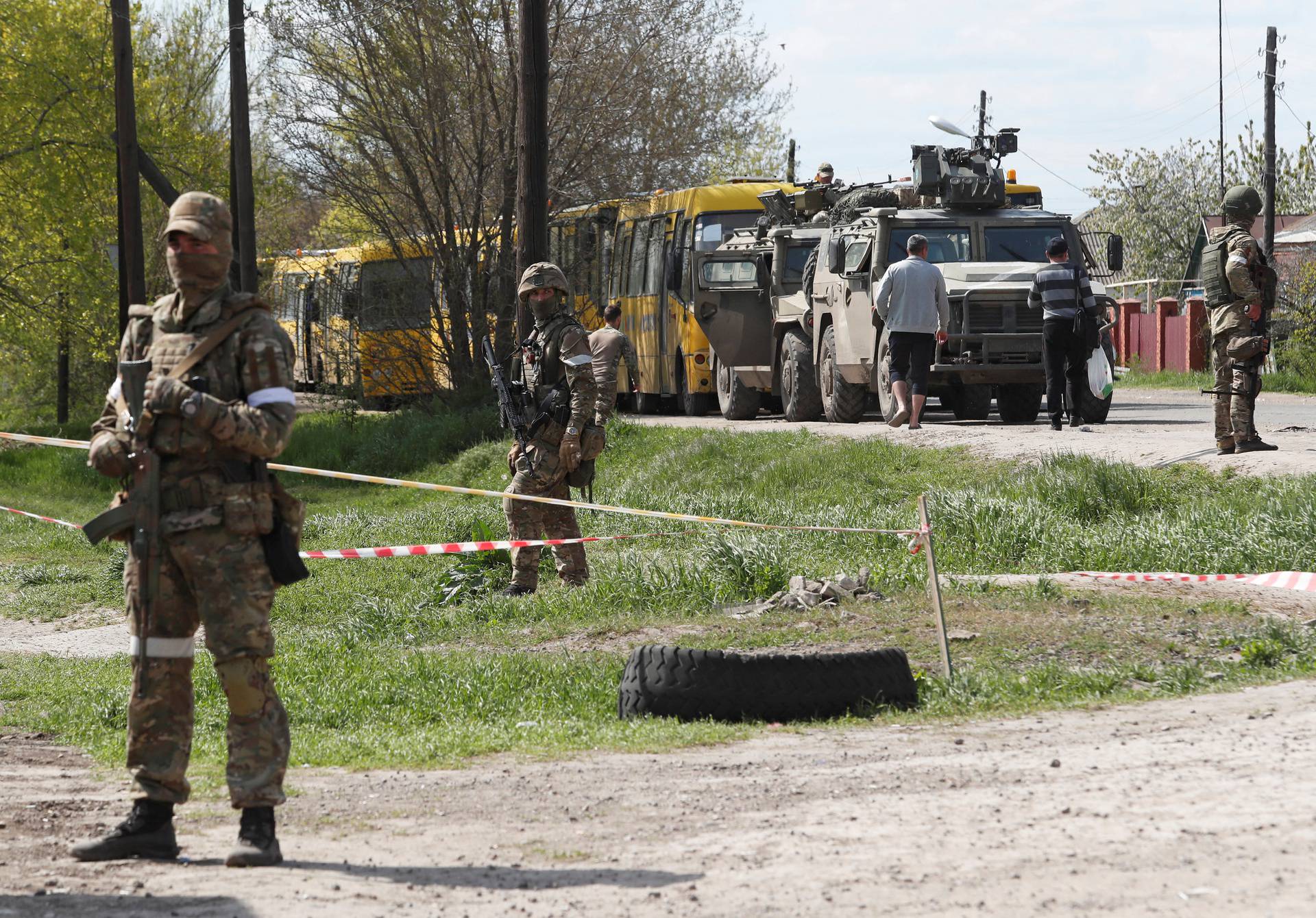 Service members of pro-Russian troops stand guard near a temporary accommodation centre for evacuees in Bezimenne