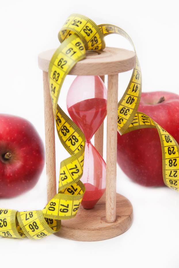 Fat Burning and Weight loss process. Diet and Fitness Concept. Red Apple and Tape Measure Isolated, close up. White Background. Vertical image.