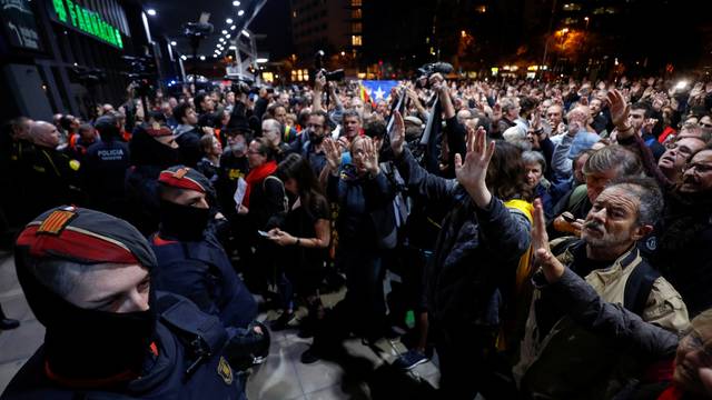 People participate in a protest as security forces stand guard outside the Sants train station in Barcelona