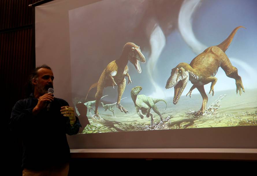 Argentine paleontologist Apesteguia speaks next to a screen showing two Cretaceous Period predatory dinosaurs named Gualicho in northern Patagonia 90 million years ago in Buenos Aires