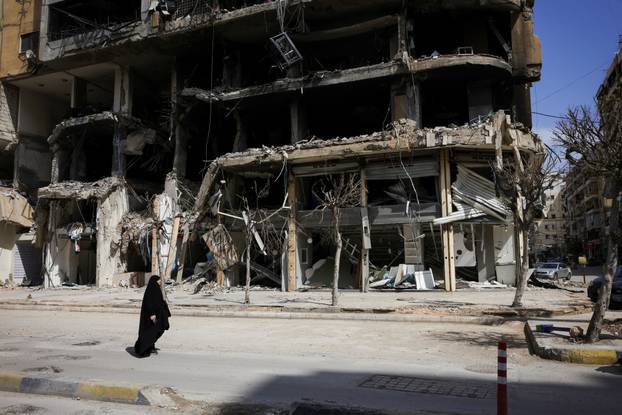 A woman walks past damaged buildings amid a 10-day ceasefire between Lebanon and Israel, in Beirut