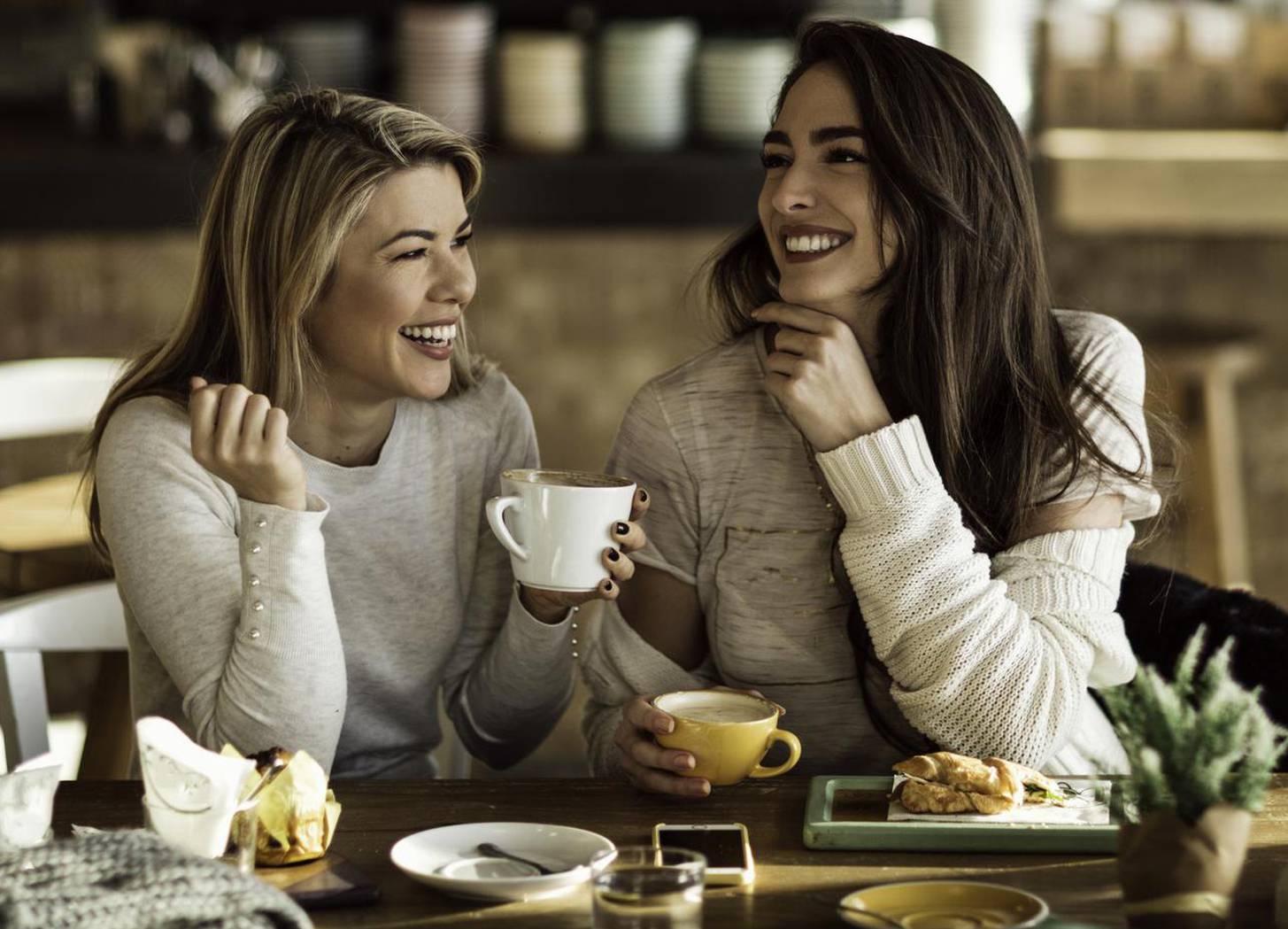 Two cheerful women having fun during coffee time in a cafe.