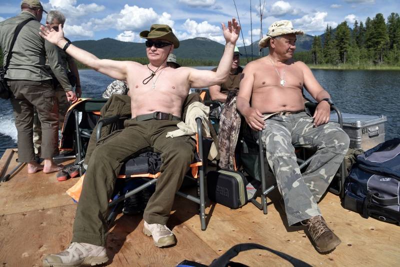 Russian President Vladimir Putin and Defence Minister Sergei Shoigu rest after fishing during the hunting and fishing trip which took place on August 1-3 in the republic of Tyva in southern Siberia